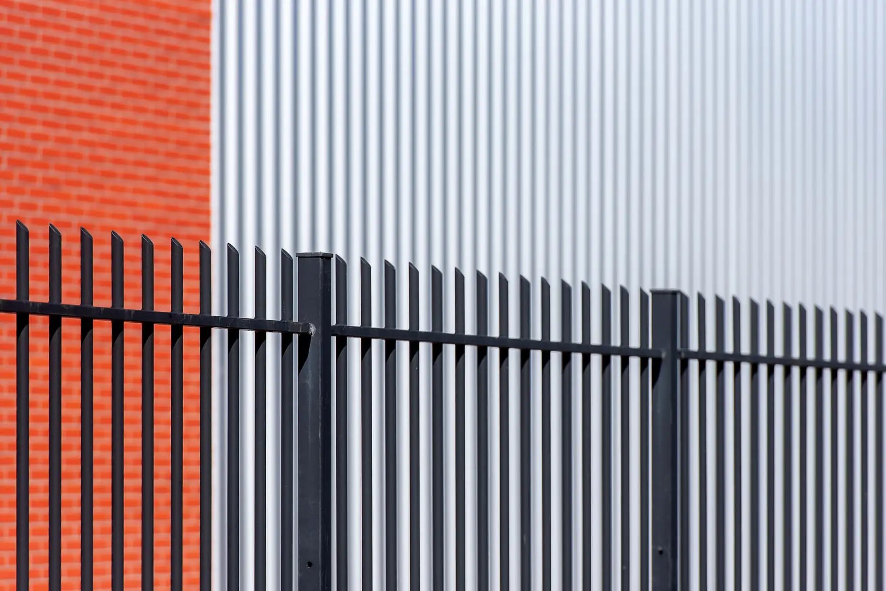 Black steel picket fence in front of red brick